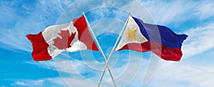 crossed national flags of Canada and Philippines flag waving in the wind at cloudy sky. Symbolizing relationship, dialog,
