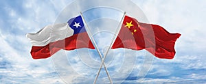 crossed national flags of Chile and china flag waving in the wind at cloudy sky. Symbolizing relationship, dialog, travelling