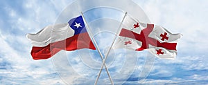 crossed national flags of Chile and Georgia flag waving in the wind at cloudy sky. Symbolizing relationship, dialog, travelling