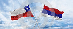 crossed national flags of Chile and Republic Srpska flag waving in the wind at cloudy sky. Symbolizing relationship, dialog,