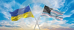 crossed national flags of Ukraine and TransAmerica flag waving in wind at cloudy sky. Symbolizing relationship, dialog, travelling