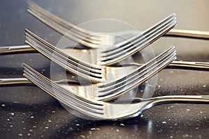 Crossed steel forks on glossy dark table.