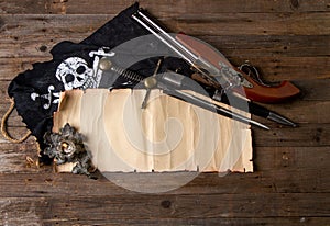 Crossed vintage flintlock pistol large pirate dagger and jolly roger flag and blank papyrus with space for text or card on