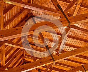 Crossed wood support trestles with their angle supporters on a ceiling. Closeup of roof rafters and cross beams of a