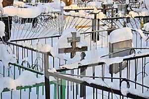 Crosses in a cemetery, monuments of the dead, a cemetery in winter, wreaths, artificial flowers. Russia