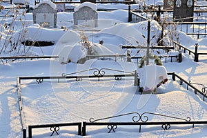 Crosses in a cemetery, monuments of the dead, a cemetery in winter, wreaths, artificial flowers. Russia