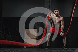 Crossfit athlete doing battle ropes exercise photo