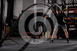 Crossfit battle ropes exercise during atlete training at modern workout gym