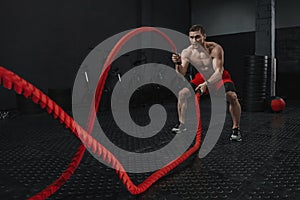 Crossfit battle ropes exercise during atlete training at the workout gym