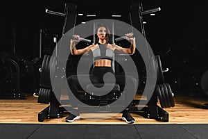 Crossfit concept, fragile girl on the background of a huge simulator with large weights, the concept of the opposite.