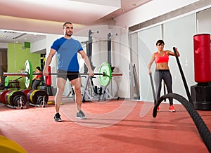 Crossfit gym weight lifting bar man woman battling ropes