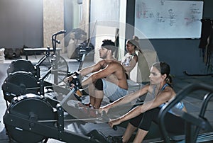 Crossfit. People Exercising On Rowing Machine In Training Gym