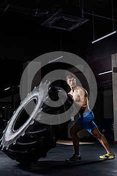 Crossfit training - man flipping tire in gym