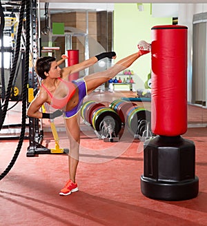Crossfit woman kick boxing with red punching bag