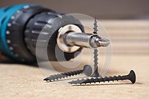 Crosshead screwdriver and self-tapping screws lie on a sheet of fiberboard