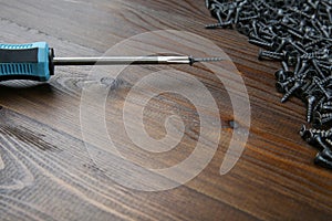 Crosshead screwdriver with wood screw on brown wooden background