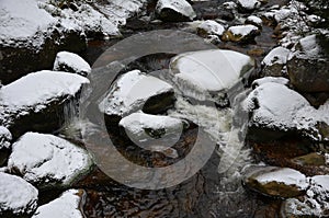 crossing a mountain stream river with large granite stones with a pram on