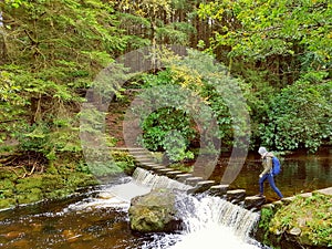 Woman Walking Over Stepping Stones Across River