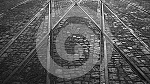 Crossing of tram rails on stone pavement in the city black and white background