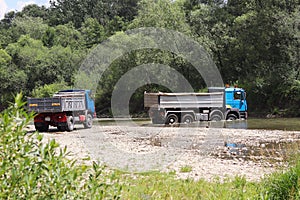 Crossing a trucks through a shallow mountain river. Transportation of goods in hard-to-reach places and dangerous conditions. Ecol