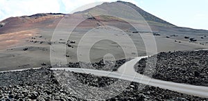 Crossoads in lunar landscape of Lanzarote with red volcanic mountains on the background, Canary Islands.