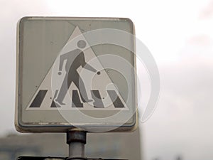 Crosswalk sign pallid faded colorless beside road