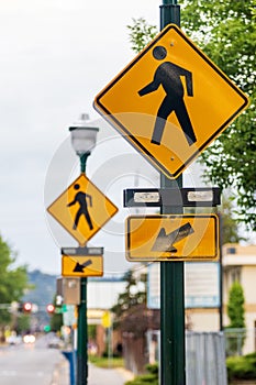 Crosswalk signs on a lamp post with arrows and a man symbol