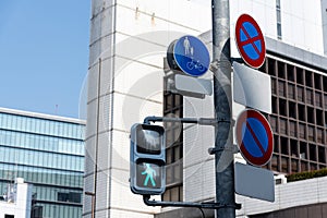 The crosswalk traffic lights and traffic signage with building background in tokyo, japan