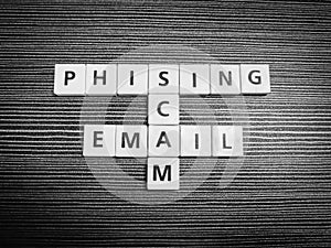 Crossword phising scam email made from square letter tiles against black background.