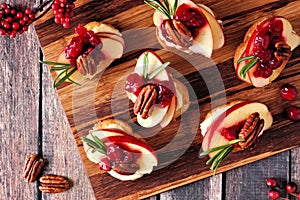 Crostini appetizers with apples, cranberries and brie, above on a wooden platter