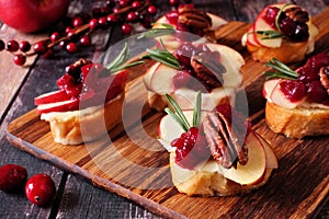 Crostini appetizers with apples, cranberries and brie, close up on a wooden platter