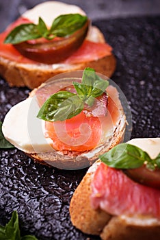 Crostini with salmon, mozarella, tomato and basil