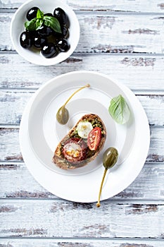 Crostini with tomato, salami and olive pesto on wooden background.