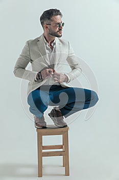 Crouched bearded man looking to side and buttoning jacket