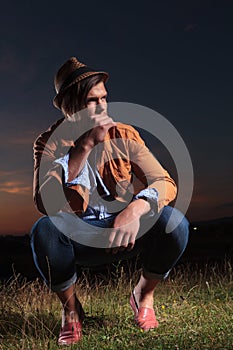 Crouched casual man holds straw in mouth