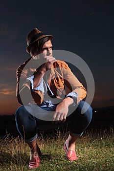 Crouched casual man holds straw in mouth photo