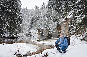 A crouching hiker by the winter river