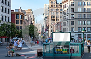 Crowd of anonymous people walking around a blank billboard sign