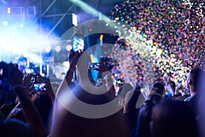 Crowd of audience with hands using camera phone to take pictures and videos at live concert, smartphone records live music festiva