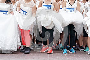 Crowd of brides prepares for their race by lining up in front of starting line, in which groom will serve as their goal. It`s a photo