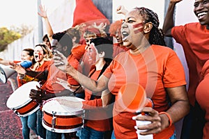 Crowd football fans exulting while watching soccer game at stadium - People with painted face and drum encouraging their team