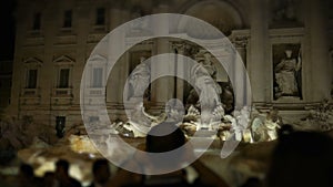 The crowd in front of the Trevi Fountain, a man shoots a fountain on the smartphone Rome night