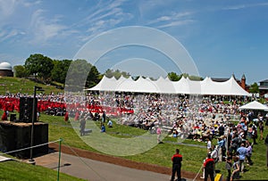 Crowd and graduates sit in front of tent at outdoor Wesleyan University Graduation Middletown Conneticut USA circa May 2015