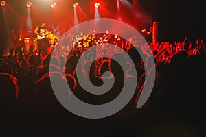 A crowd of happy people raising up hands at an open-air rock concert.