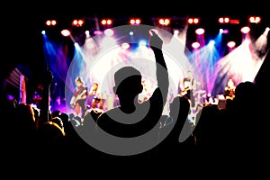 A crowd of happy people raising up hands at an open-air rock concert.