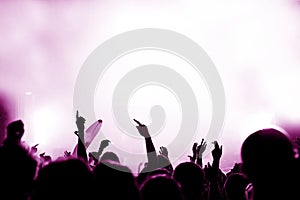 Crowd at a music concert, audience raising hands up, toned