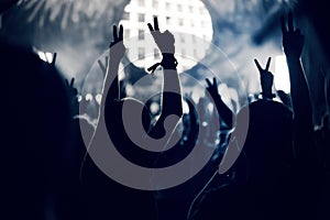 Crowd at a music concert, audience raising hands up, toned