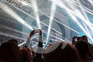 A crowd of people at the concert have fun and dance to the music at the concert. Gray background and beams. Rear view. The concept