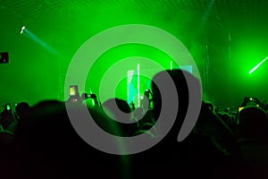 A crowd of people at the concert have fun and dance to the music at the concert. Green background. Rear view. The concept of