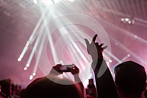 A crowd of people at the concert have fun and dance to the music at the concert. Pink light in background. The concept of